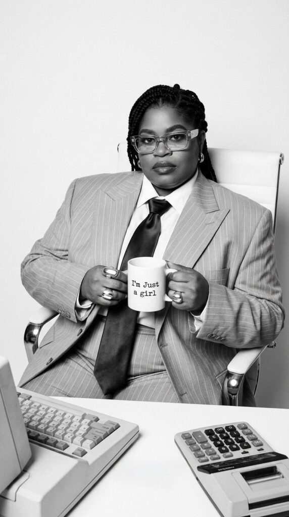 Genie wearing a suit and tie drinking coffee at a desk.